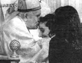 Jan Paweł II całuje kobietę w czoło.